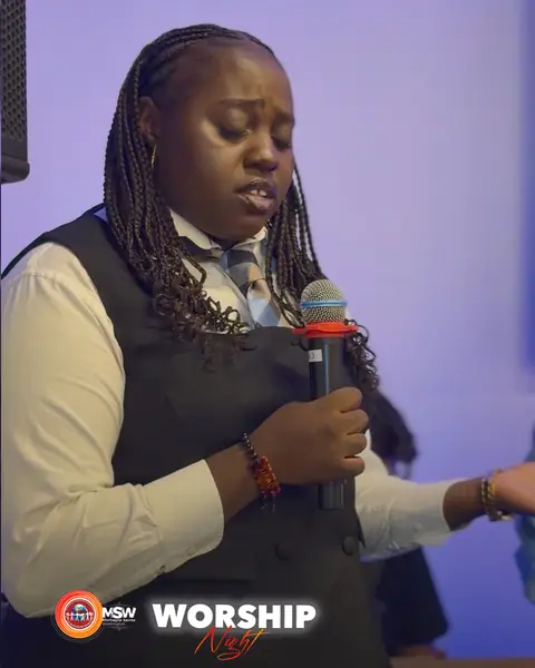 A worship leader singing with her eyes closed, holding a microphone