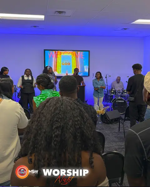 The worship team leading the congregation, a screen behind them reading Welcome to the presence of God